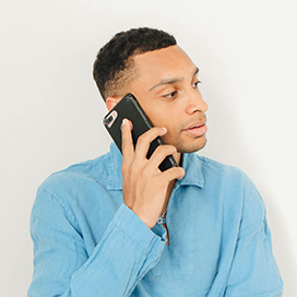 A man in a blue shirt holding a phone to his ear
